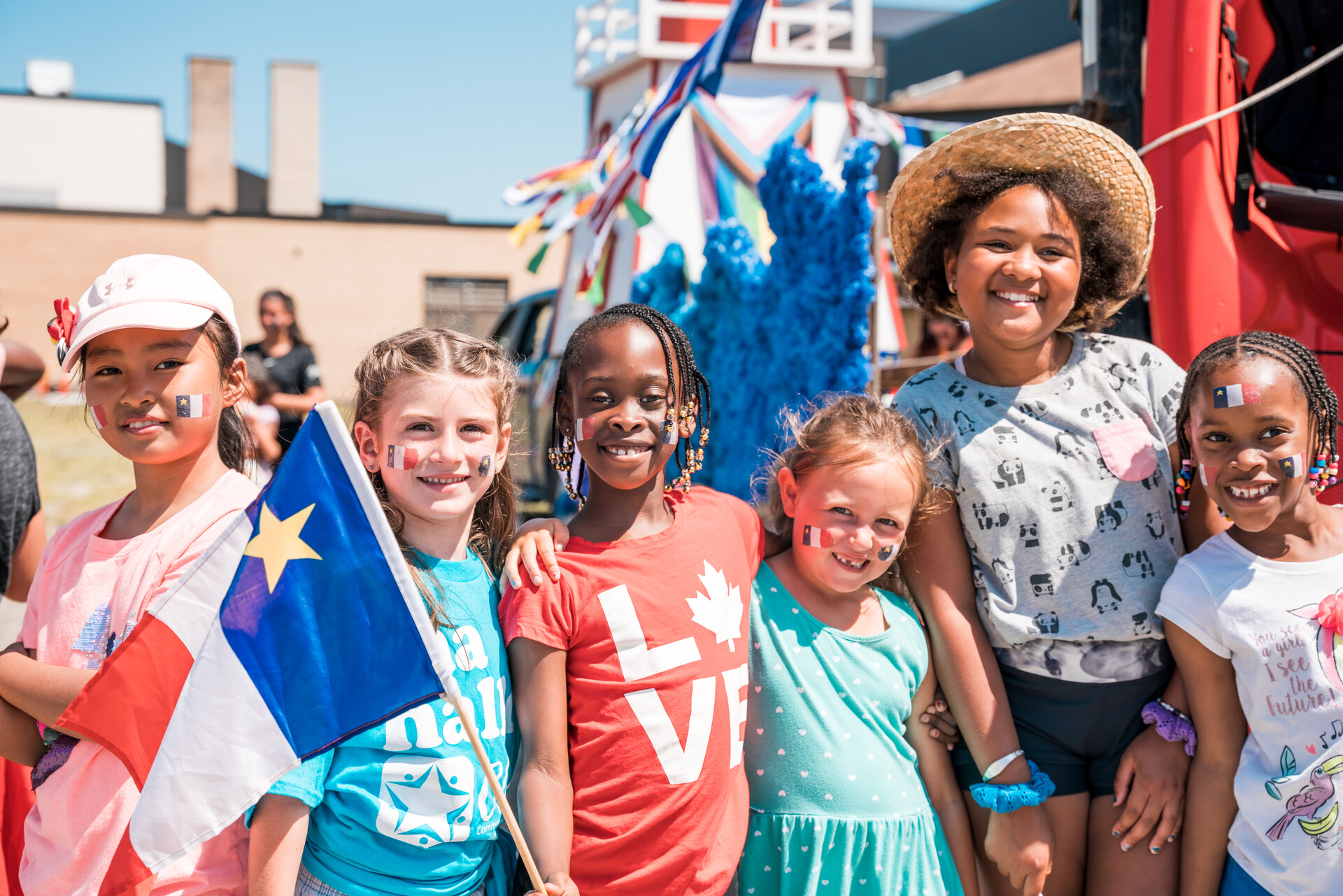 Une photo de jeunes filles de différents origines réunies devant un char de parade.