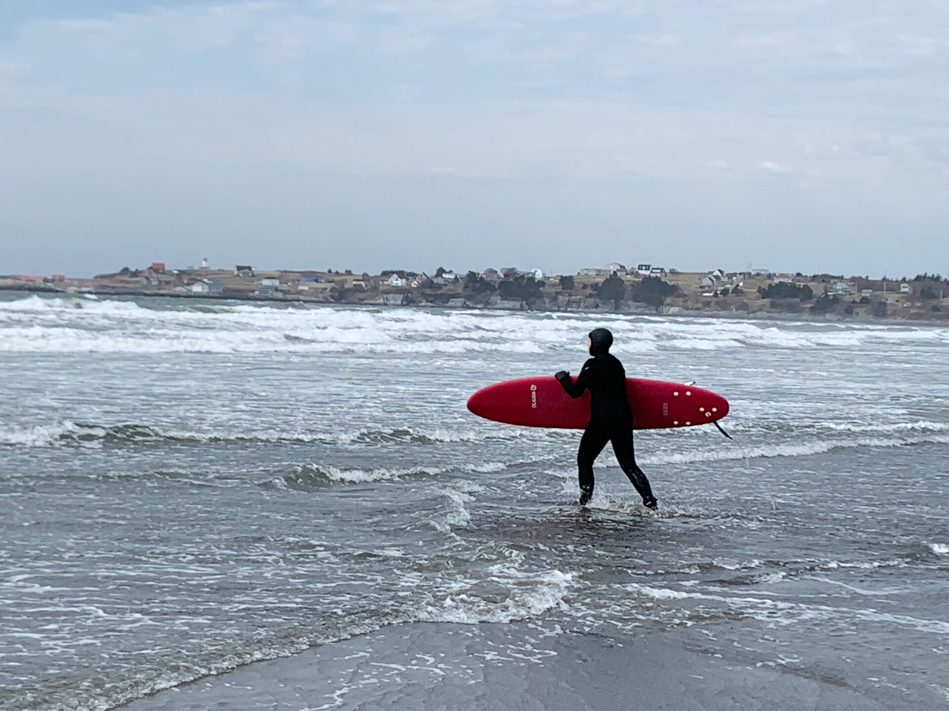 Person with surf board standing in the ocean