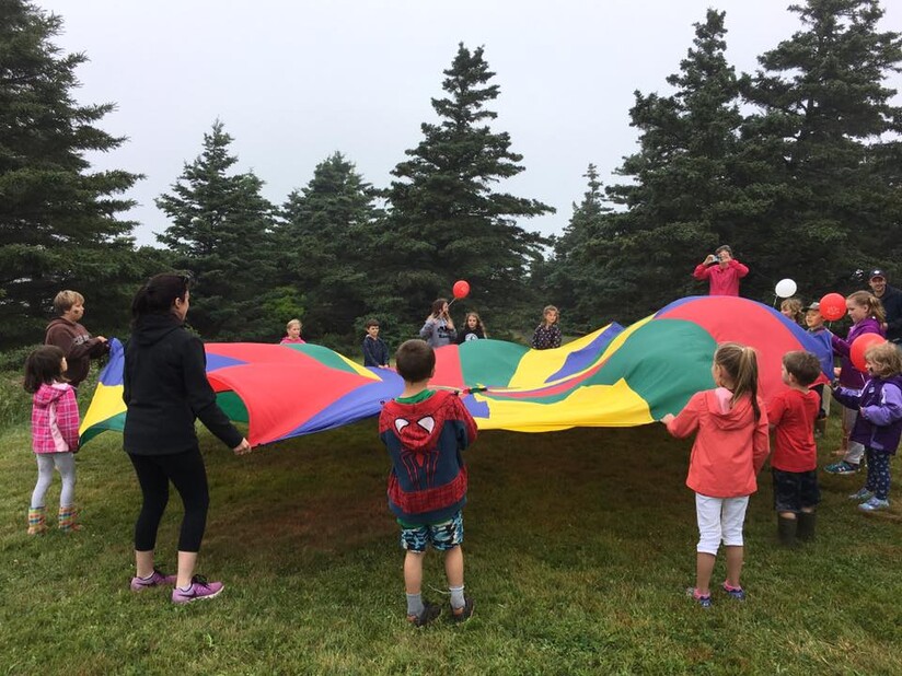 Des enfants en cercle tenant un parachute